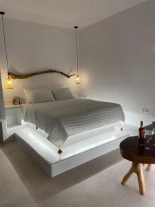 a white bedroom with a bed with a white bed frame at Heliopetra Punta in Ios Chora