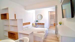 a white bedroom with a bed and a desk at Mamaia-Nord Boutique Apartments in Mamaia Sat/Năvodari