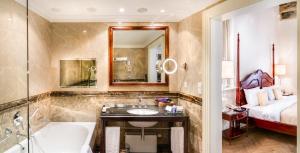 a bathroom with a tub and a sink and a bed at The Dominican in Prague