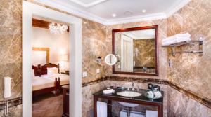 a bathroom with a sink and a mirror and a bed at The Dominican in Prague