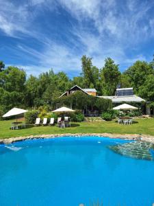 a large pool with chairs and umbrellas in front of a house at Hostal Macal in Talca