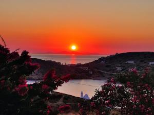 a sunset over a body of water with the sun setting at Heliopetra Punta in Ios Chora