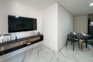 a living room with a table and a television on a wall at Aconchegante Térreo Bessa 4 pessoas 200m da Praia in Nossa Senhora do Livramento
