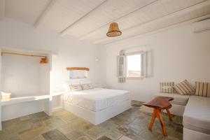a white bedroom with a bed and a couch at Heliopetra Punta in Ios Chora