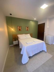 ViVale suítes في أرايال دو كابو: سرير أبيض كبير في غرفة ذات جدار أخضر