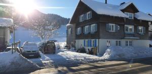 a snow covered house with cars parked in front of it at Gemütliches 2 Bettzimmer mit Gemeinschaftsbad und kleiner Küche in Alberschwende