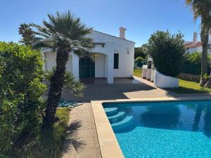 a villa with a palm tree and a swimming pool at Villa Isabel in Cala'n Bosch +6 photos