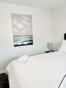 a bedroom with a white bed with a painting on the wall at Elegant Brand New Apartment in Central Burlington in Burlington