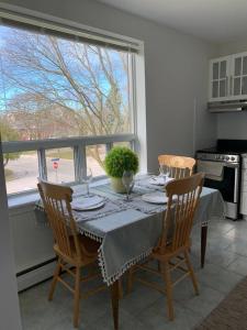 a dining room table with four chairs and a window at Elegant Brand New Apartment in Central Burlington in Burlington