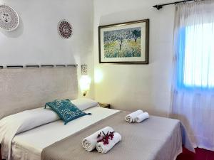 two beds in a hotel room with towels on them at Rosso Lilu' Casa con vista mozzafiato sulla Pelosa in Stintino