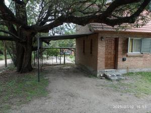 a house with a wooden door and a tree at Los Cachilos in Merlo