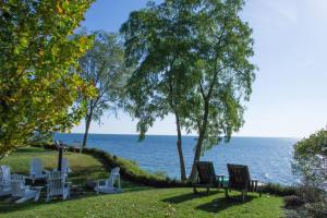 a group of chairs sitting on the grass near the water at Luxury waterfront fairytale home -Carmen Elisabeth in Burlington