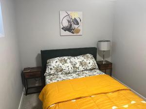 a bedroom with a bed with a yellow blanket at Private Basement Suite with comfort in Winnipeg