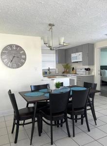 une salle à manger avec une table, des chaises et une horloge dans l'établissement Fully Fenced With Hot tub near Siesta Key Bridge, à Sarasota