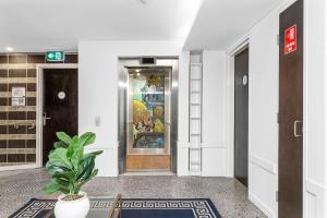 a hallway with a potted plant in front of a refrigerator at Nest on Newcastle - E2 in Perth