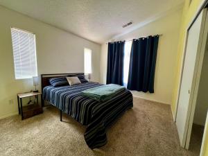 a bedroom with a bed and a window with blue curtains at Paradise Skies in Albuquerque