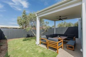 a patio with a couch and a table in a yard at Olive Grove - stroll to the beach! in Ocean Grove