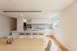 a kitchen with white cabinets and a table and chairs at Olive Grove - stroll to the beach! in Ocean Grove
