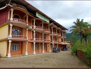 a large building with cars parked in front of it at Sri DURGAMBA COMFORTS in Kalasa