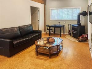 a living room with a black leather couch and a table at Sq Gretas Place in Sequim