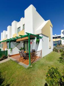 a white house with a patio with a table and chairs at Bungalow Capri Maspalomas in San Bartolomé