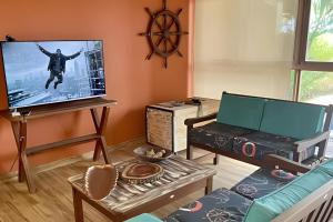 ein Wohnzimmer mit Flachbildfernseher und Couch in der Unterkunft LC Casas de Praia Jardim dos Guajirus in Tamandaré