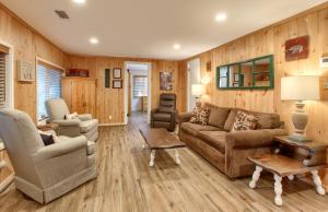 a living room with wooden walls and a couch and chairs at The Little Creek Cabin in Wawona