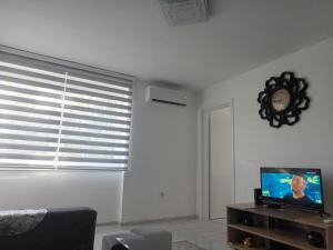 a living room with a tv and a clock on the wall at Ajša apartmani in Sarajevo