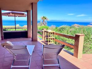 zwei Stühle und ein Sonnenschirm auf einer Terrasse mit Meerblick in der Unterkunft Villa Corallo con vista mozzafiato in Costa Paradiso
