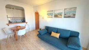 a living room with a blue couch and a table at Arenales Sea View Apartment in Arenales del Sol