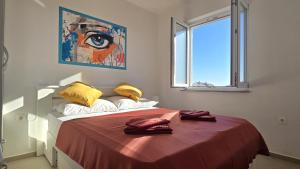 een slaapkamer met een bed met rode lakens en een raam bij CRYSTAL WAVE Apartments in Novalja