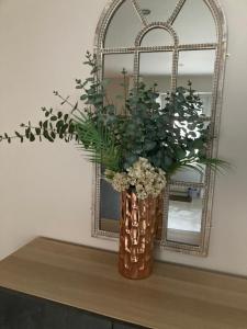 a vase with flowers on a table in front of a mirror at Dalys Back House in Béal Átha Póirin