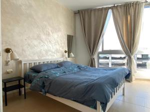 una camera da letto con un letto con lenzuola blu e una finestra di bat-yam 2 Bedrooms on the beach a Bat Yam