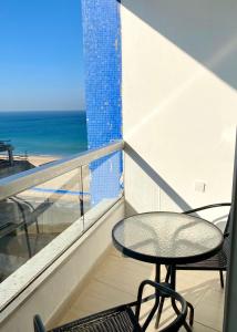 un tavolo e una sedia su un balcone con vista sull'oceano di bat-yam 2 Bedrooms on the beach a Bat Yam