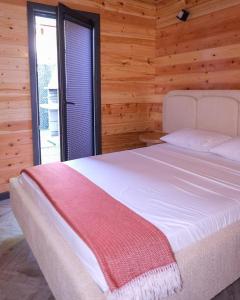 a bedroom with a white bed with a wooden wall at Bell Garden Maşukiye in Kocaeli +19 photos