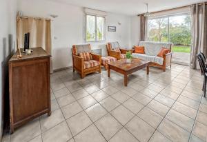 a living room with a couch and chairs and a tv at Maison cosy avec grand jardin in Saint-Avé