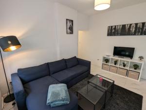 ein Wohnzimmer mit einem blauen Sofa und einem Fernseher in der Unterkunft Nord-Apartment 5 I 1 Zimmer mit einladendem Wohnbereich im Erdgeschoss in Bremerhaven