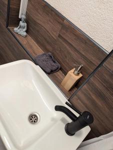 ein weißes Waschbecken in einem Badezimmer mit einem Spiegel in der Unterkunft Nord-Apartment 5 I 1 Zimmer mit einladendem Wohnbereich im Erdgeschoss in Bremerhaven