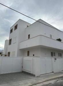 a white building with a fence in front of it at Gaia apartments in Porto Cesareo