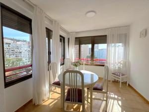 uma sala de jantar com mesa, cadeiras e janelas em Loixmar 7 em Benidorm