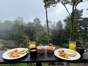 two plates of food on a wooden table with drinks at Nido Bag Glamping in Cali