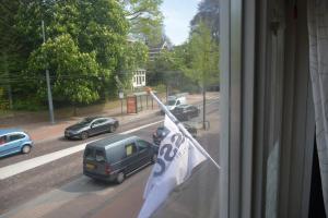 Aussicht aus einem Fenster einer Straße mit parkenden Autos in der Unterkunft Three bedroom lovely apartment in Oosterbeek