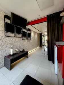 a living room with a couch and a tv on the wall at Cap Red Room in Cap d'Agde
