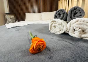 una flor naranja en una cama con toallas en Amber Apartment Nice - Central Highlights and Beach, en Niza