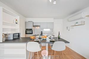 Casa Tropezina by BLOSS familieappartement met terras في أوستند: مطبخ مع خزائن بيضاء وطاولة وكراسي +13 صورة