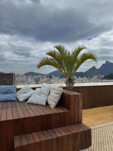 a wooden bench with pillows on a balcony with a palm tree at Breathtaking Views from Rio Duplex Penthouse in Rio de Janeiro