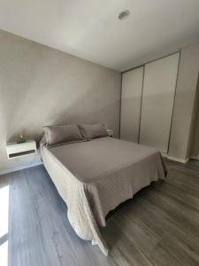 een slaapkamer met een groot bed en een houten vloer bij Depto céntrico en Pinamar con parrilla y piscina en la terraza in Pinamar
