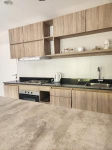 een keuken met houten kasten en een aanrechtblad bij Depto céntrico en Pinamar con parrilla y piscina en la terraza in Pinamar +8 foto's