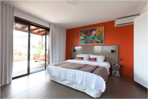 - une chambre avec un grand lit et un mur orange dans l'établissement Hotel Ker Alberte, à Cayenne