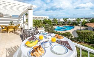 een tafel met ontbijtproducten op een balkon met een zwembad bij Ona Village Cala d'Or in Cala d´Or